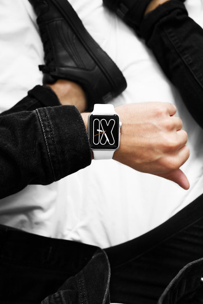 A man in black outfit showcases a white smartwatch with a stylish digital face.