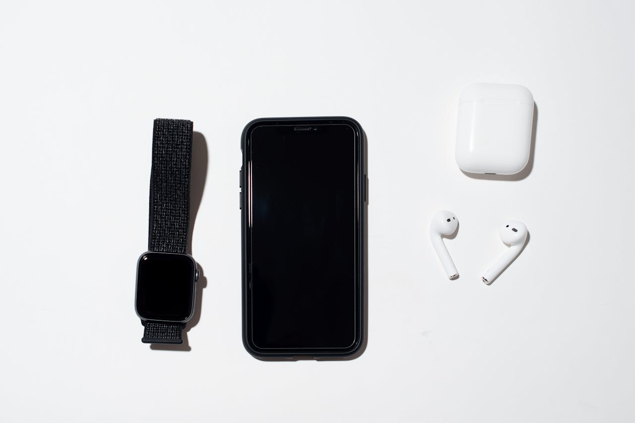 heros-img Top view of true wireless earphones with case on white background with black smartphone and smart watch